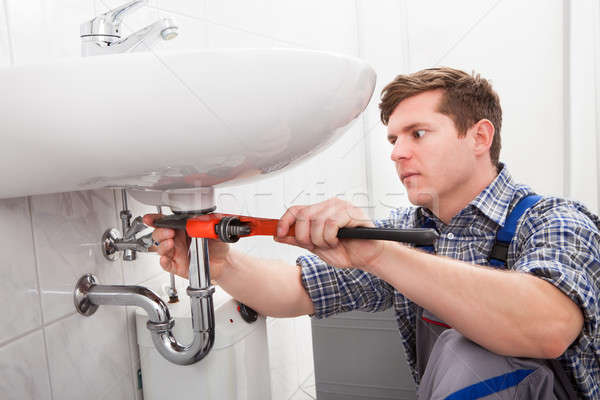 Stock photo: Portrait of male plumber fixing a sink
