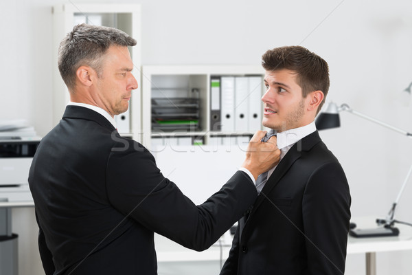 Mature Businessman Gripping Employee's Tie Stock photo © AndreyPopov
