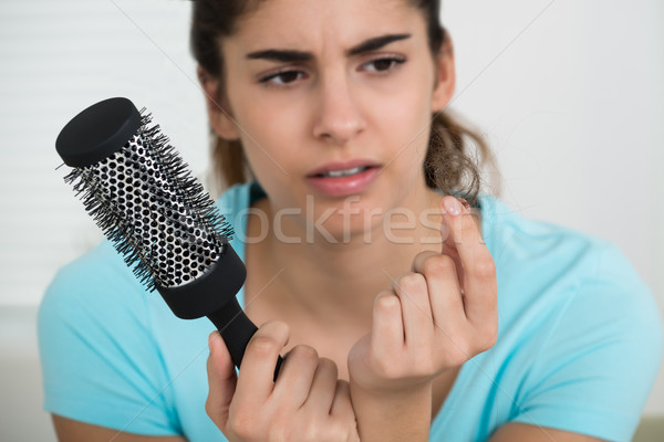 Woman Holding Comb While Looking At Hair Loss Stock photo © AndreyPopov