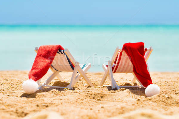 Two Deck Chairs With Santa Hats On Beach Stock photo © AndreyPopov