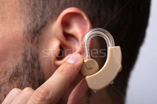Stock photo: Man Inserting Hearing Aid In His Ear