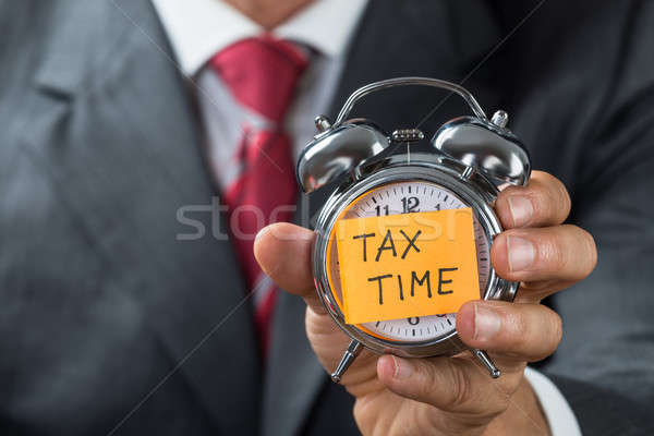 Businessman Holding Alarm Clock With Tax Time Note Stock photo © AndreyPopov