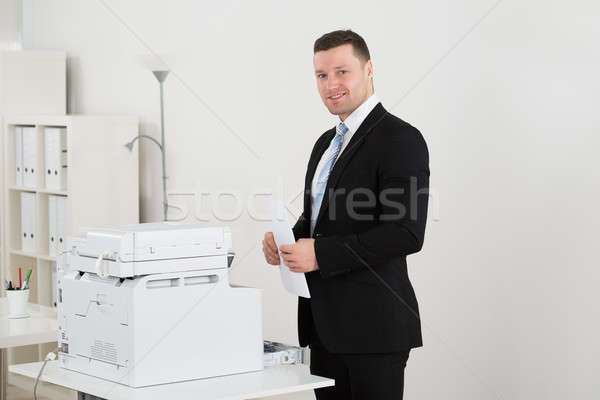 Happy Businessman Holding Paper By Photocopy Machine Stock photo © AndreyPopov