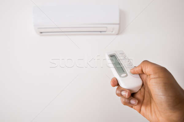 Stock photo: Person's Hand Holding Remote To Operate Air Conditioner