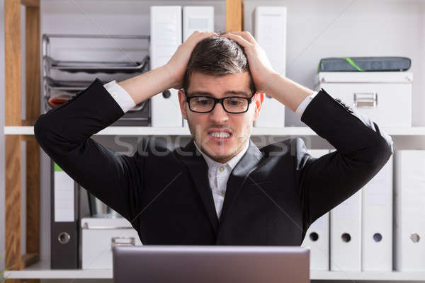 Frustrado empresário jovem olhando laptop Foto stock © AndreyPopov