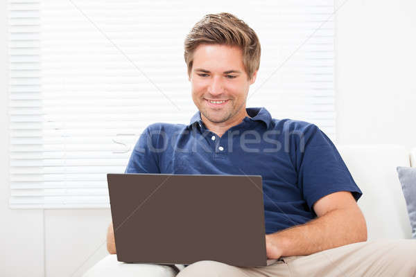 Man Using Laptop On Sofa At Home Stock photo © AndreyPopov