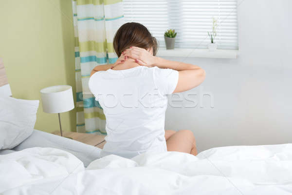 Mujer dolor de cuello sesión cama habitación Foto stock © AndreyPopov