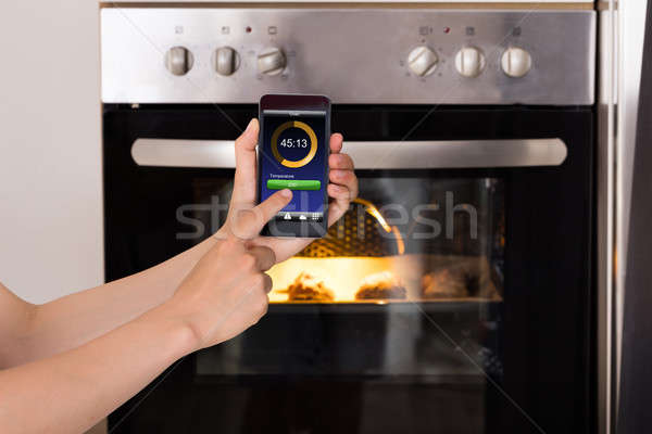 Person Operating Oven Appliance With Mobile Phone Stock photo © AndreyPopov