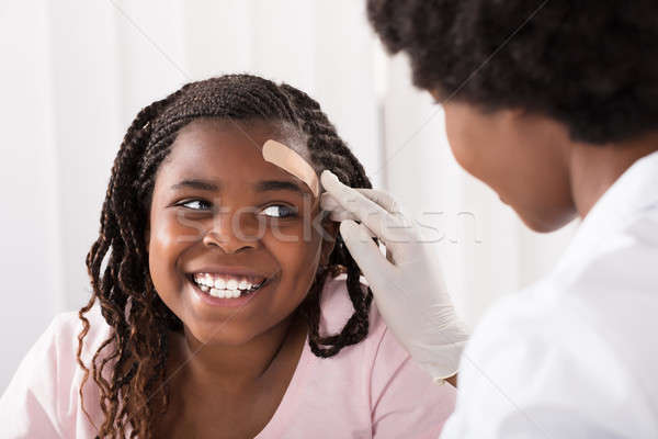 Doctor Applying Band Aid To Girl Head Stock photo © AndreyPopov