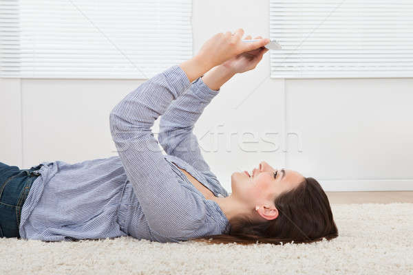 Woman Using Digital Tablet While Lying On Rug Stock photo © AndreyPopov