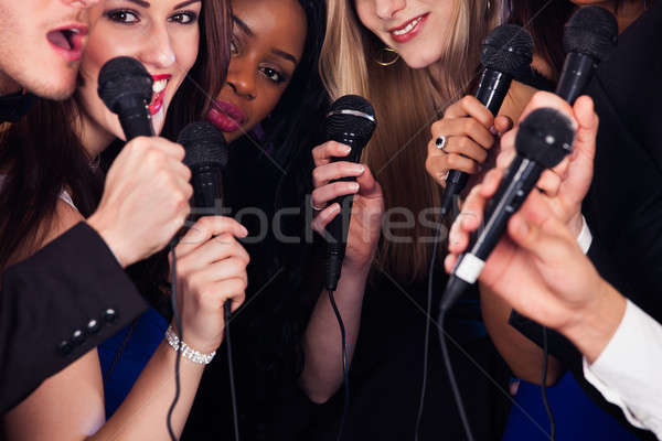 Friends Singing Into Microphones At Karaoke Party Stock photo © AndreyPopov