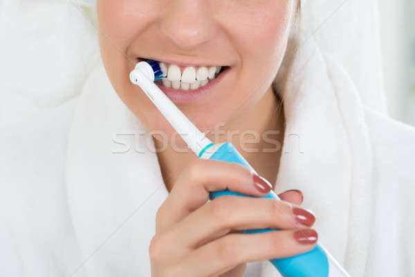 Nő fürdőköpeny fogmosás elektromos fogkefe közelkép Stock fotó © AndreyPopov