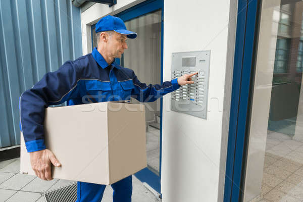 Delivery Man Pressing Button Of Intercom To Enter Building Stock photo © AndreyPopov