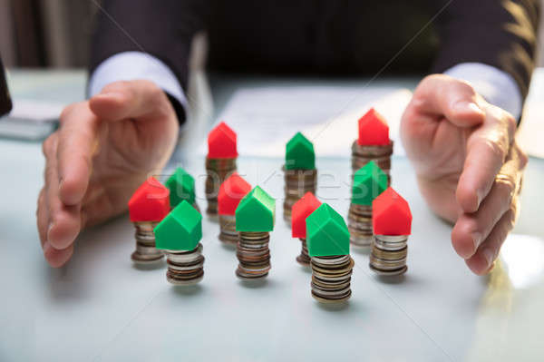 Businessperson Protecting House Models On Stacked Coins Stock photo © AndreyPopov