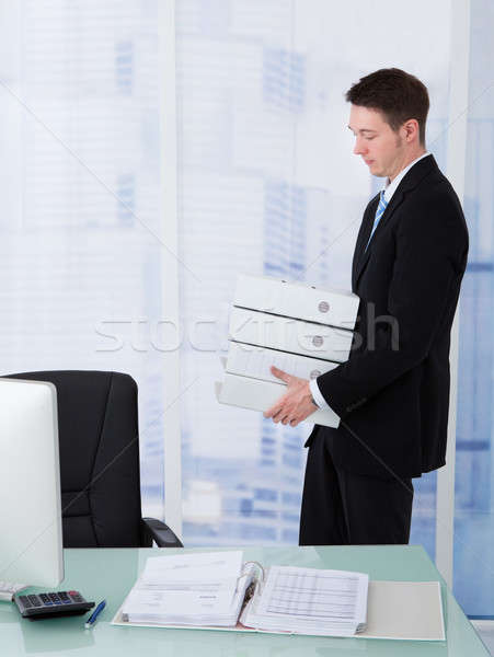 Businessman Carrying Stacked Binders At Desk Stock photo © AndreyPopov