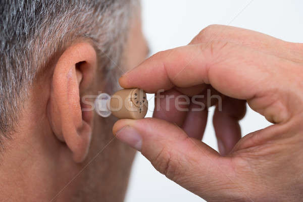 Closeup Of Businessman Inserting Hearing Aid In Ear Stock photo © AndreyPopov