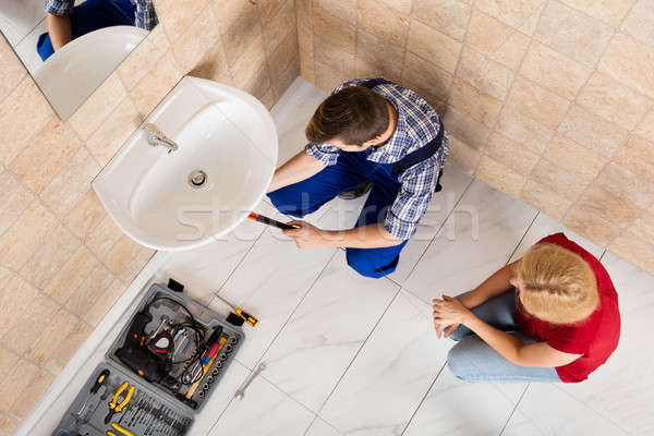 Young Male Plumber Fixing Sink In Bathroom Stock photo © AndreyPopov
