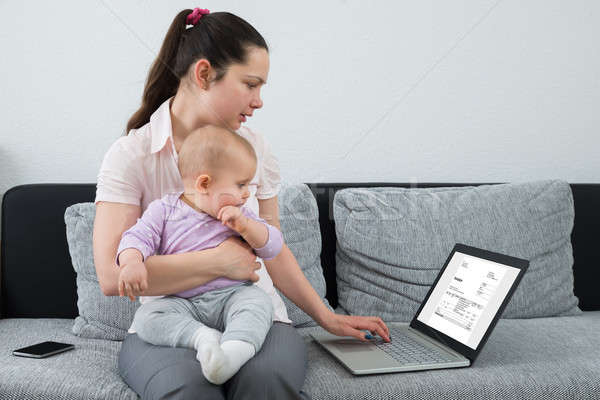 Kobieta rachunek laptop posiedzenia sofa baby Zdjęcia stock © AndreyPopov