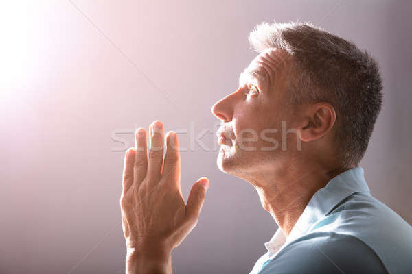 Primer plano rezando hombre maduro fiel divino luz Foto stock © AndreyPopov