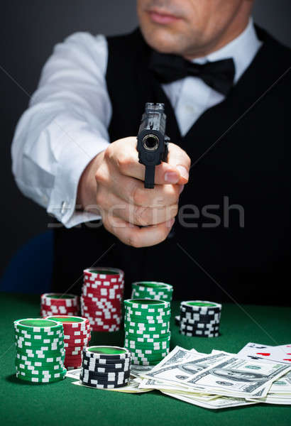 Portrait of a croupier aiming with a gun Stock photo © AndreyPopov