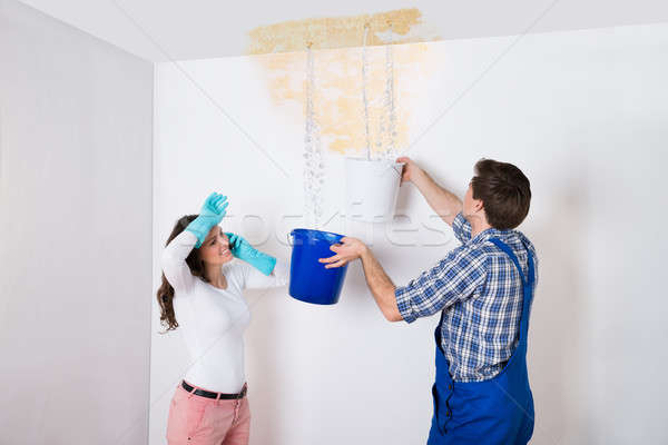 Woman With Worker Collecting Water From Ceiling In Bucket Stock photo © AndreyPopov
