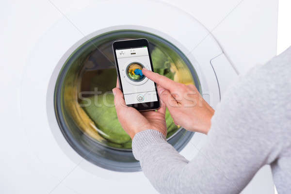 Woman Using Mobile Phone To Operate Washing Machine Stock photo © AndreyPopov