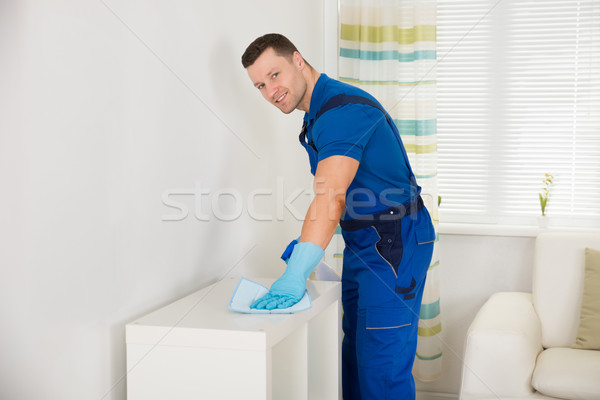 Smiling Janitor Cleaning Shelf With Sponge At Home Stock photo © AndreyPopov