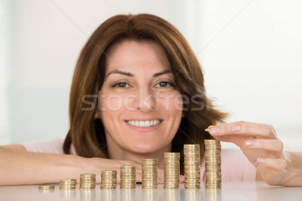 Happy Woman Stacking Coins At Desk Stock photo © AndreyPopov