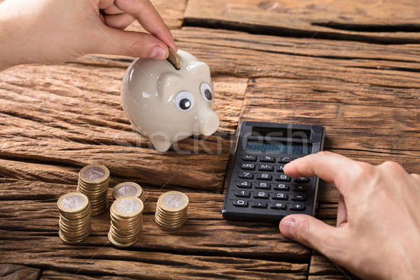 Person Calculating On Calculator With Coins And Piggy Bank Stock photo © AndreyPopov