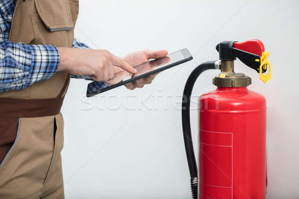 Technician Using Digital Tablet To Check Fire Extinguisher Stock photo © AndreyPopov