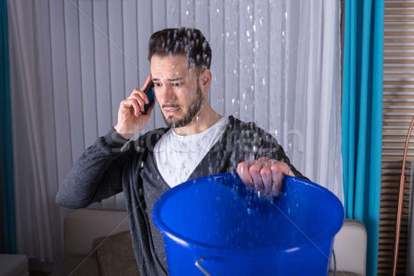 Hombre recoger agua cubo llamando fontanero Foto stock © AndreyPopov
