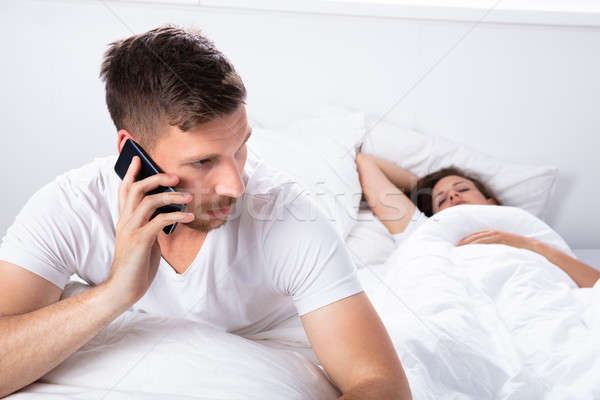 若い男 話し 携帯電話 妻 寝 ベッド ストックフォト © AndreyPopov
