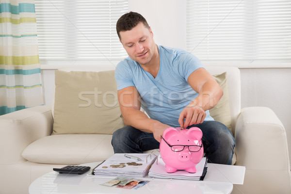Man Putting Coin Into Piggy Bank At Home Stock photo © AndreyPopov