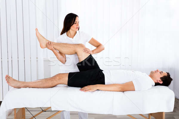 Stock photo: Young Female Masseur Giving Leg Massage To Man
