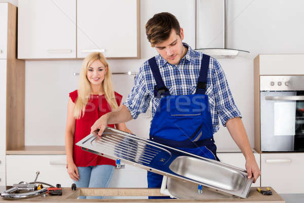 Male Plumber Fixing Stainless Steel Sink In Kitchen Stock photo © AndreyPopov