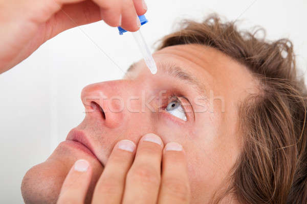 Young Man Putting Eye Drops Stock photo © AndreyPopov