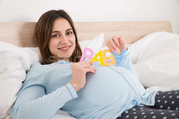 Pregnant Woman With Text Baby Lying On Bed Stock photo © AndreyPopov