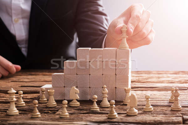 Businessperson Arranging Chess Piece On Wooden Blocks Stock photo © AndreyPopov