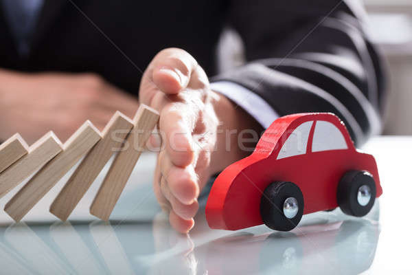 Businessperson's Hand Stopping Wooden Blocks From Falling On Car Stock photo © AndreyPopov