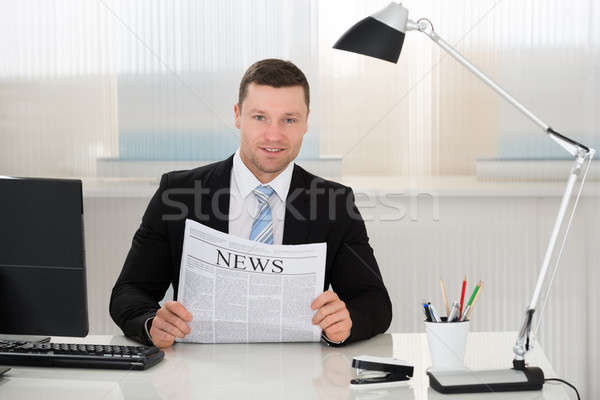 Businessman Holding Newspaper At Desk In Office Stock photo © AndreyPopov