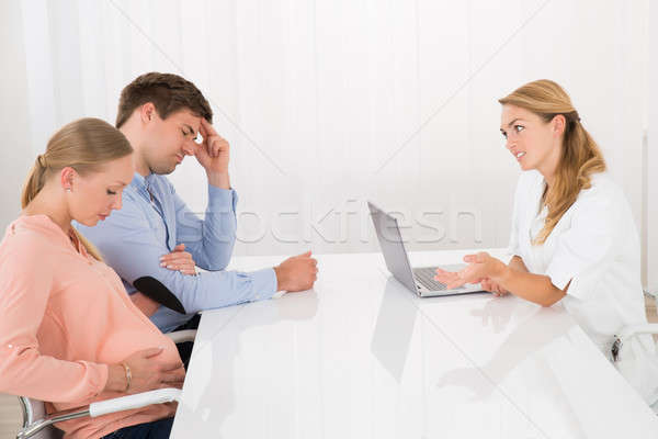 Doctor Consoling Young Couple Expecting Baby Stock photo © AndreyPopov