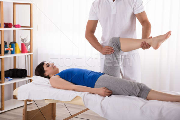 Woman Lying On Bed Receiving Leg Massage Stock photo © AndreyPopov
