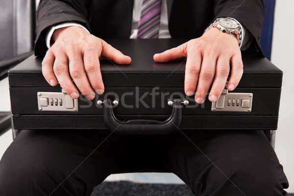 Businessman sitting and holding briefcase Stock photo © AndreyPopov