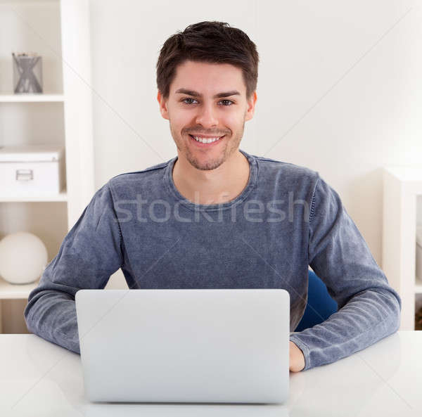 Smiling young man using a laptop Stock photo © AndreyPopov
