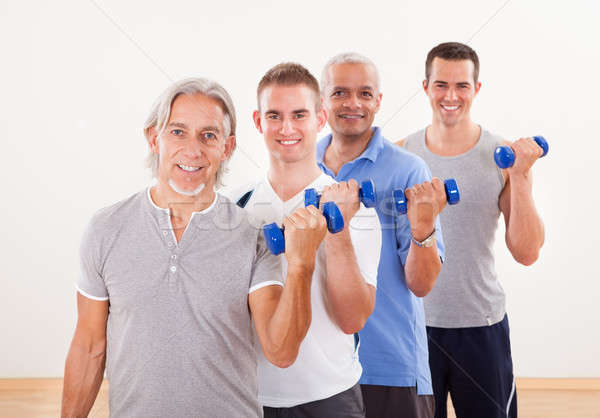 Row of men working with dumbbells Stock photo © AndreyPopov