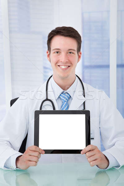 Stock photo: Confident Doctor Displaying Digital Tablet At Desk