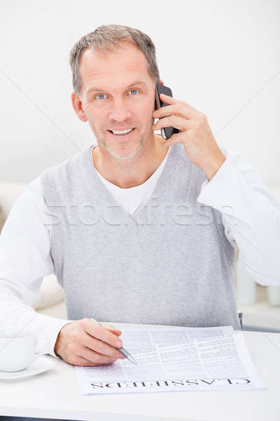 Férfi újság beszél mobiltelefon olvas apróhirdetések Stock fotó © AndreyPopov