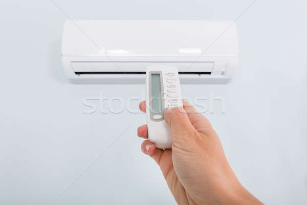 Stock photo: Person Operating Air Conditioner With Remote Control