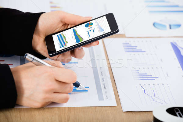 Businesswoman With Mobilephone Analyzing Graph Stock photo © AndreyPopov