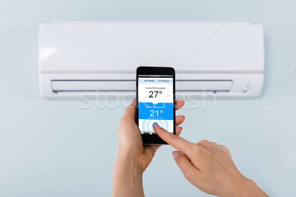 Person Hand Holding Mobilephone Near Air Conditioner Stock photo © AndreyPopov